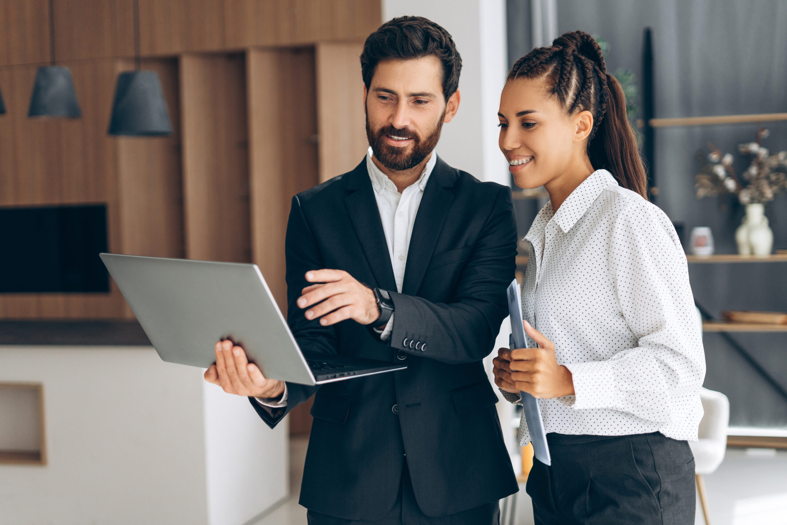Portrait of smiling, happy businessman and secretary at workplace, using laptop, planning project in modern office. Technology concept, successful business